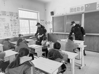           民警为孩子们发放安全知识宣传手册 本报记者 康乐 摄        