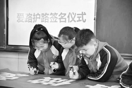           学生在宣传条幅上郑重签下名字 图片由中国铁路太原局集团公司团委提供        