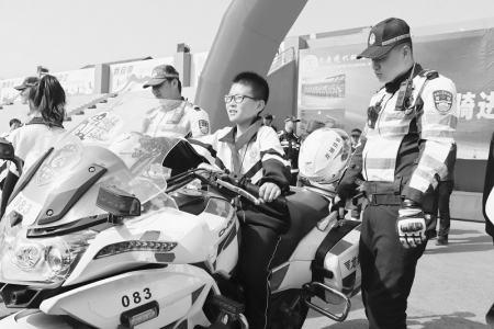           部分学生在铁骑骑手的指导下，骑上摩托车，与骑手合影留念。        