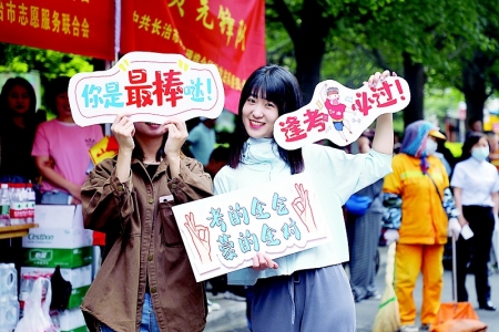           长治一中考点外，助考志愿者手举标语牌为考生加油。 本报记者 刘琴 摄        